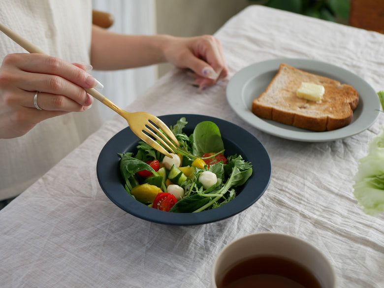 サラダが盛られたSAKUZANのSaraプレートとボウルがテーブル上に配置されている写真