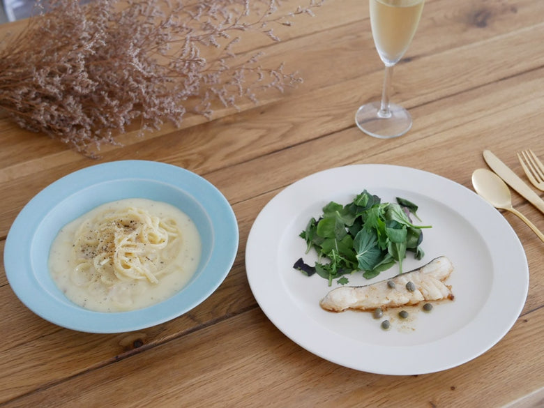 SAKUZANのSaraシリーズ磁器製プレートとボウルがテーブルに美しく配置され、色とりどりの野菜や料理が盛り付けられている様子