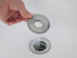 洗面台の排水口に取り付けられたヒューバス HUBATH 洗面台ヘアーキャッチャー。銀色のステンレスとプラスチック製のパーツが特徴。