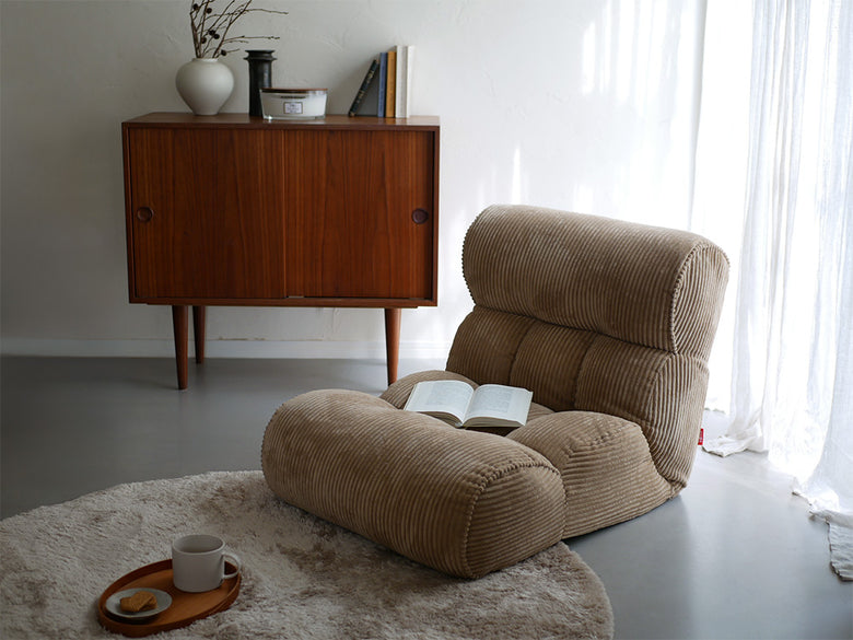 リビングルームの木製フロアに置かれたピグレットの茶色いソファータイプ座椅子