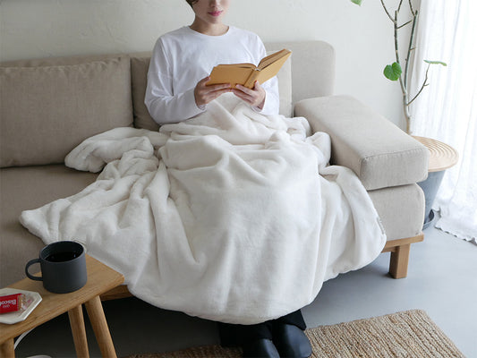 LALACAララカの洗えるなめらか素材ヒーターブランケットがリビングルームの家具やクッションと共に配置され、快適な空間を演出している様子
