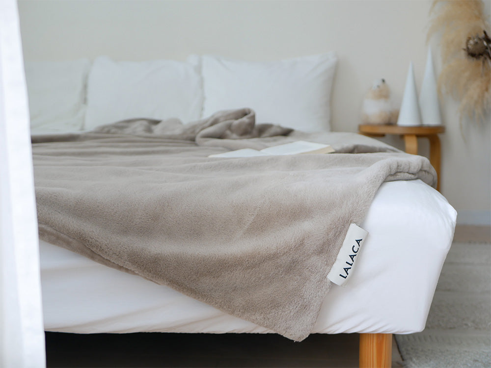 LALACAの洗えるなめらか素材のヒーターブランケットが敷かれたベッドとカラフルなクッションが配置された寝室