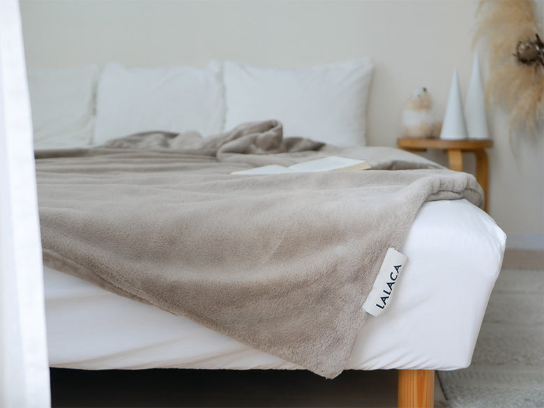 LALACAの洗えるなめらか素材のヒーターブランケットが敷かれたベッドとカラフルなクッションが配置された寝室