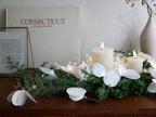 クリスマスのセンターピースとして飾られた紙製LEDキャンドル「Moon Light Tall」とキャンドルホルダー、常緑樹