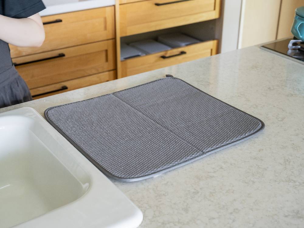 キッチンカウンター上に置かれたbws SELECTIONのすっきり暮らす水切りマット。シルバーのメッシュ素材で調理器具を整理しています。