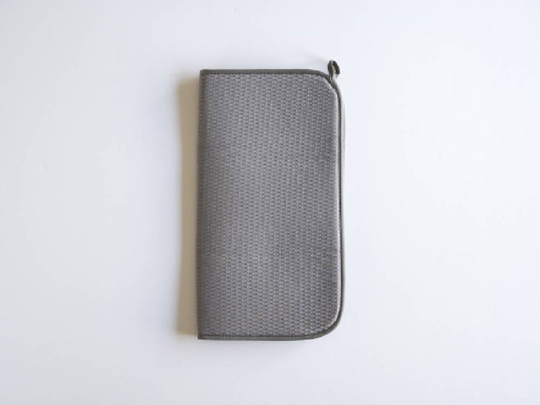 シルバーのレザー製バッグと財布、コインパース、携帯電話ケース、オフィス用品がメッシュやプラスチック素材で整理され、ファスナーで閉じられている様子