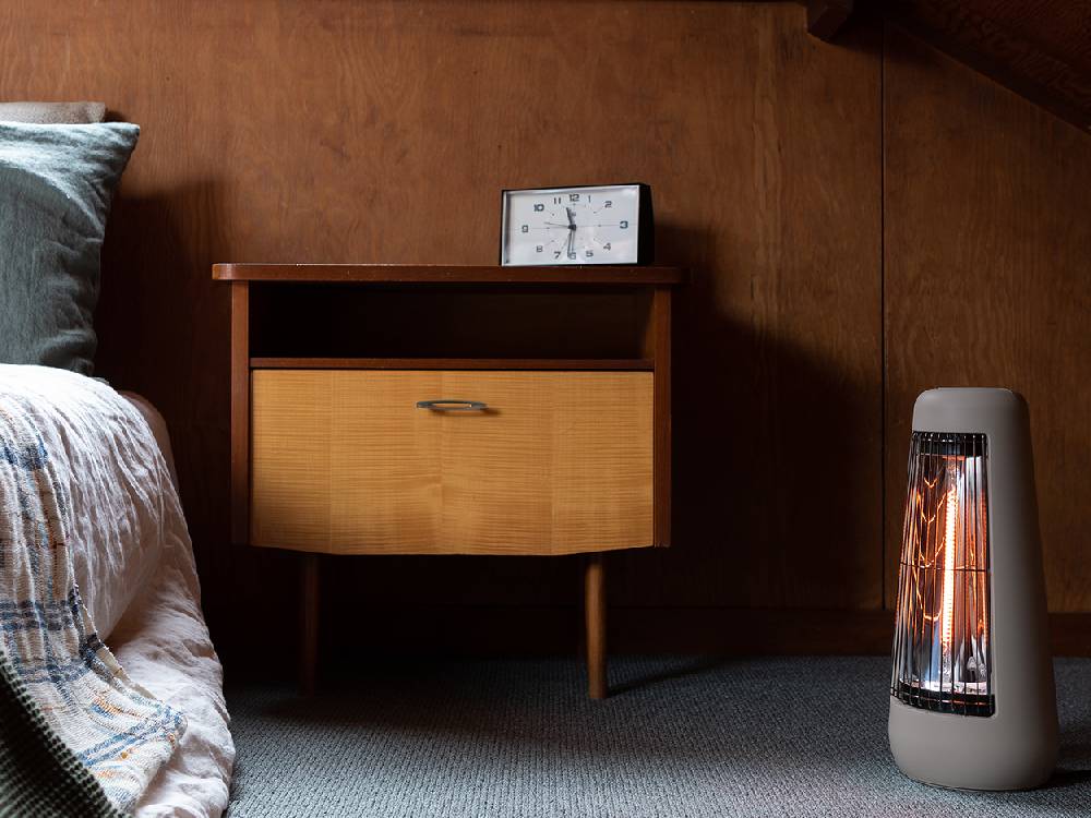 プラスマイナスゼロ カーボンヒーター H210 白色の円筒形家庭用電化製品が木目調の床の上に設置されている