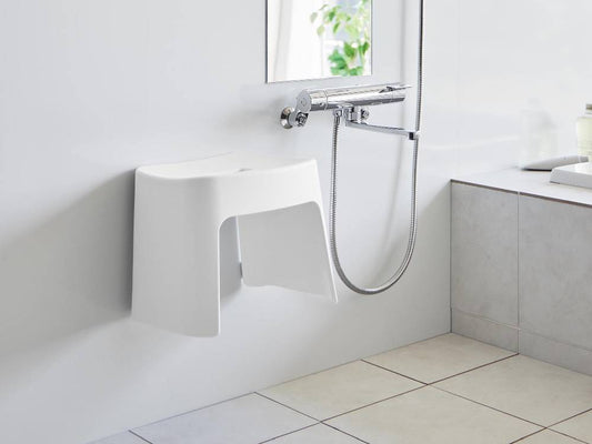 白色のtower洗いやすいマグネット風呂イスが浴室の壁に取り付けられている