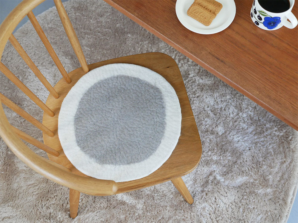 リビングルームの木製椅子に敷かれたニュージーランドウール100％のウールフェルトチェアシート。ハードウッドの床とクッションがアクセントになっています。