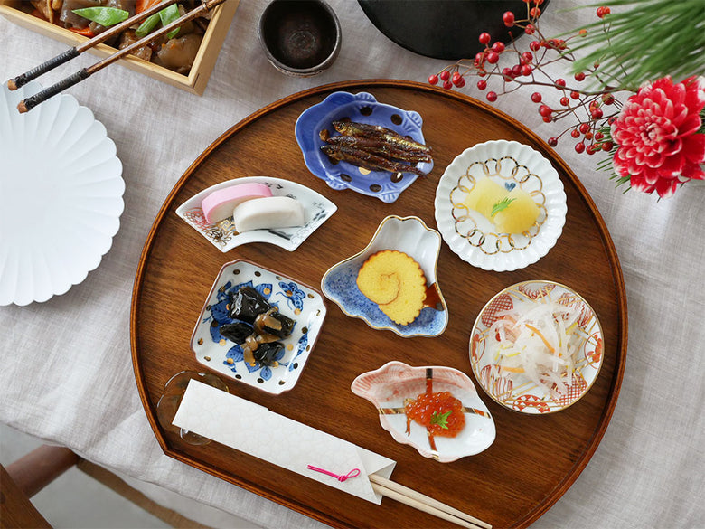 アマブロ MAME の磁器製ディナーウェアセット。吹墨富士形皿や丸散赤丸など、様々なデザインのプレートがトレーに並べられている