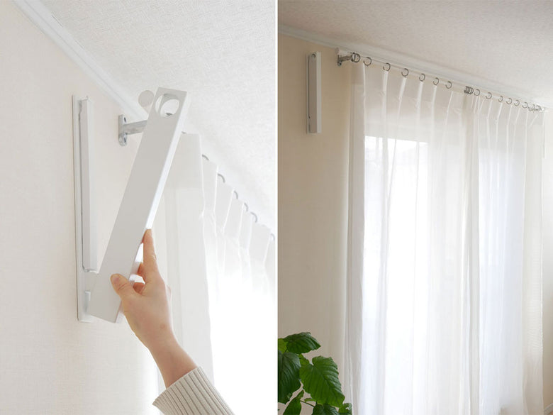 リビングルームの石膏ボード壁に設置された折り畳み物干し竿ホルダー