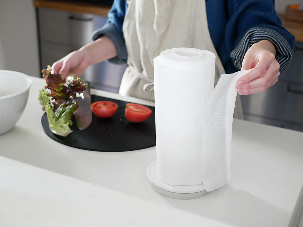 マーナの倒れない片手用キッチンペーパーホルダーがキッチンカウンターにしっかり吸着され、キッチンペーパーを保持している様子