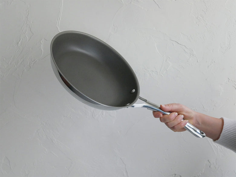 コレールのこびりつきにくいステンレス鋼とアルミニウム製のフライパンおよび中華鍋が並んだシルバーのキッチン調理器具セット