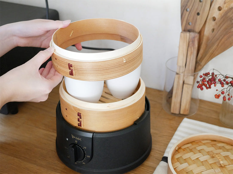 ほったらかし電気せいろに盛られた料理と木製せいろがキッチンに並ぶ様子