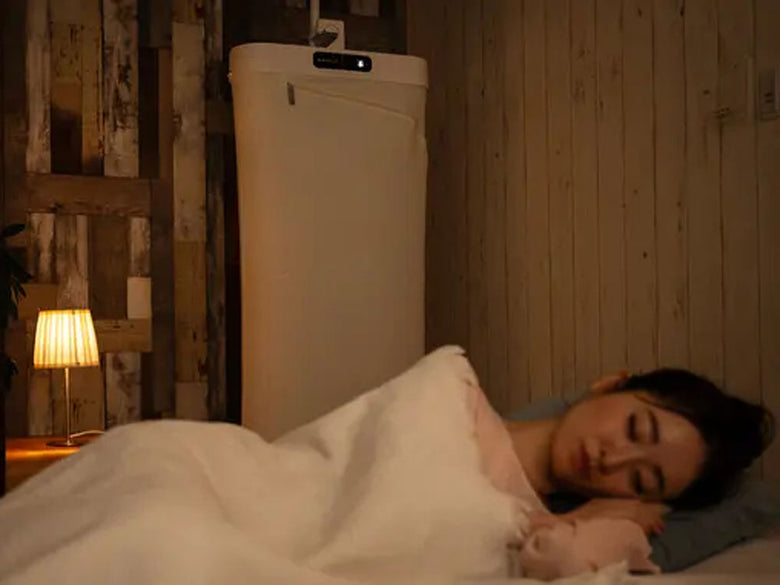 ESTILOエスティロスチームイオンリフレッシャーが配置されたベッドルーム。テキスタイルや照明、ベッドが整った快適な空間が映し出されています。