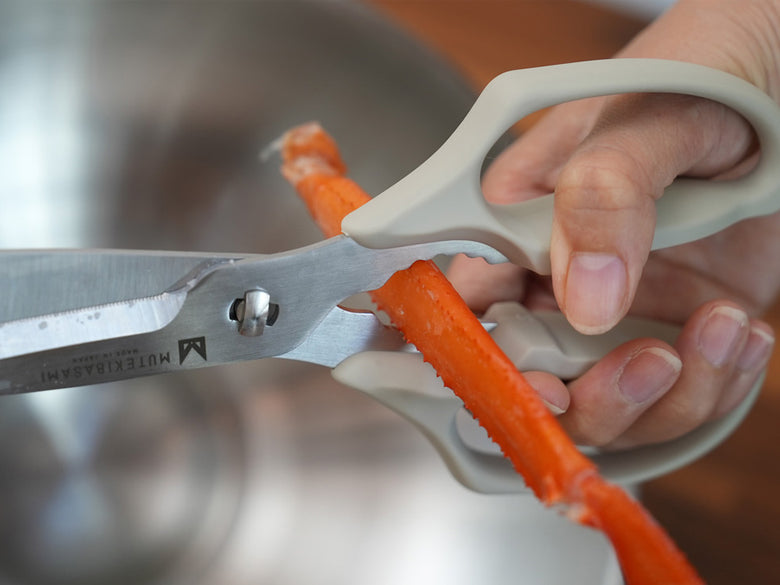 ステンレス製の協和工業ムテバサミがカッティングボード上に置かれ、料理準備中の様子