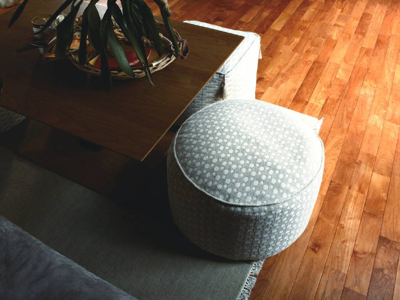 木製フロアに置かれた灰色のフレンチリネンビーズクッションオットマン