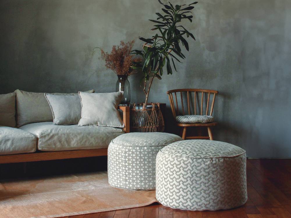 灰色のリネン製フレンチビーズクッションが木目調の家具と共にリビングルームに配置されています。