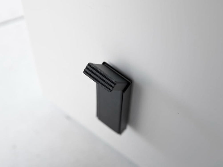 スチール製のマグネット折りたたみドアストッパー「tower」の正面画像。粉体塗装された本体にシリコーン製の滑り止めが付いており、コンパクトに折りたためるデザインです。