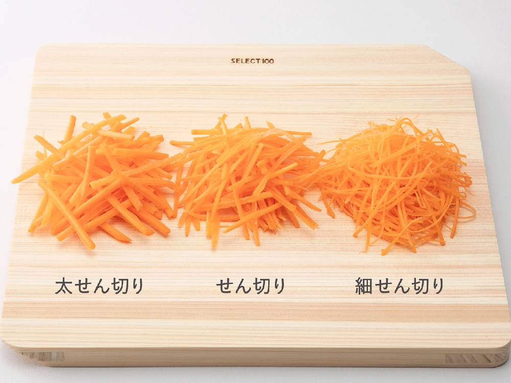 カッティングボードの上でセレクト100のせん切り器を使用し、野菜やチーズを切っている様子
