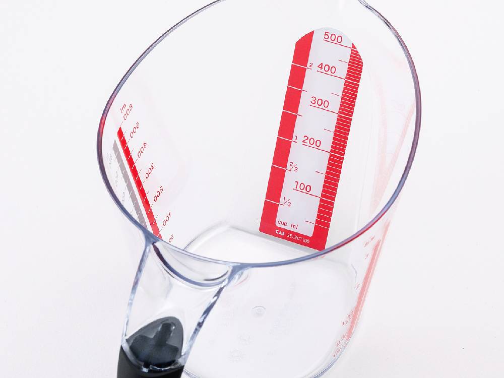 透明なプラスチック製600ml計量カップ。目盛りが刻まれており、日本製の耐熱・耐冷性キッチン用ツール。