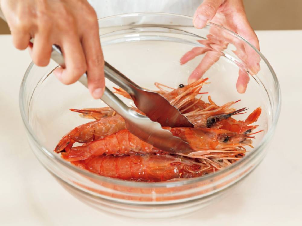 シーフードブイヨンでエビや貝を調理するために使用されているセレクト100の24cmステンレス製トング