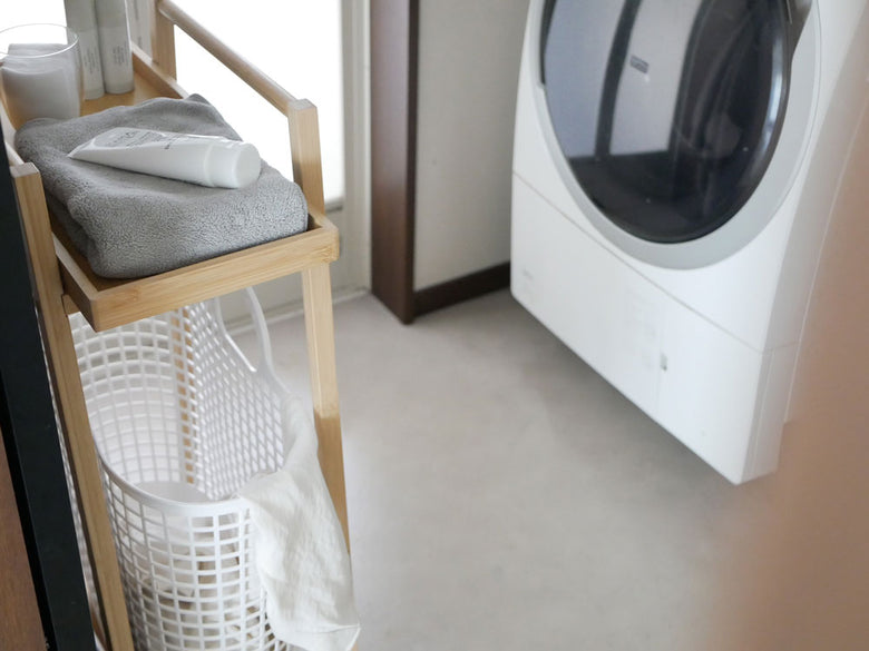 洗濯室の木製床に置かれた竹製ランドリーワゴンとバスケット