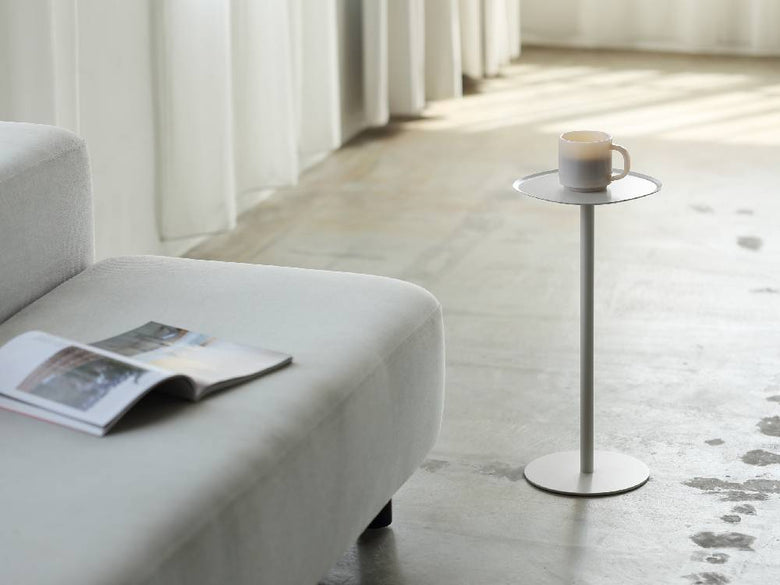 リビングルームに設置されたイデアコのスチールファニュチャー サイドテーブル23。テーブル上にはランプと花瓶が置かれ、周囲に観葉植物が配置されています。