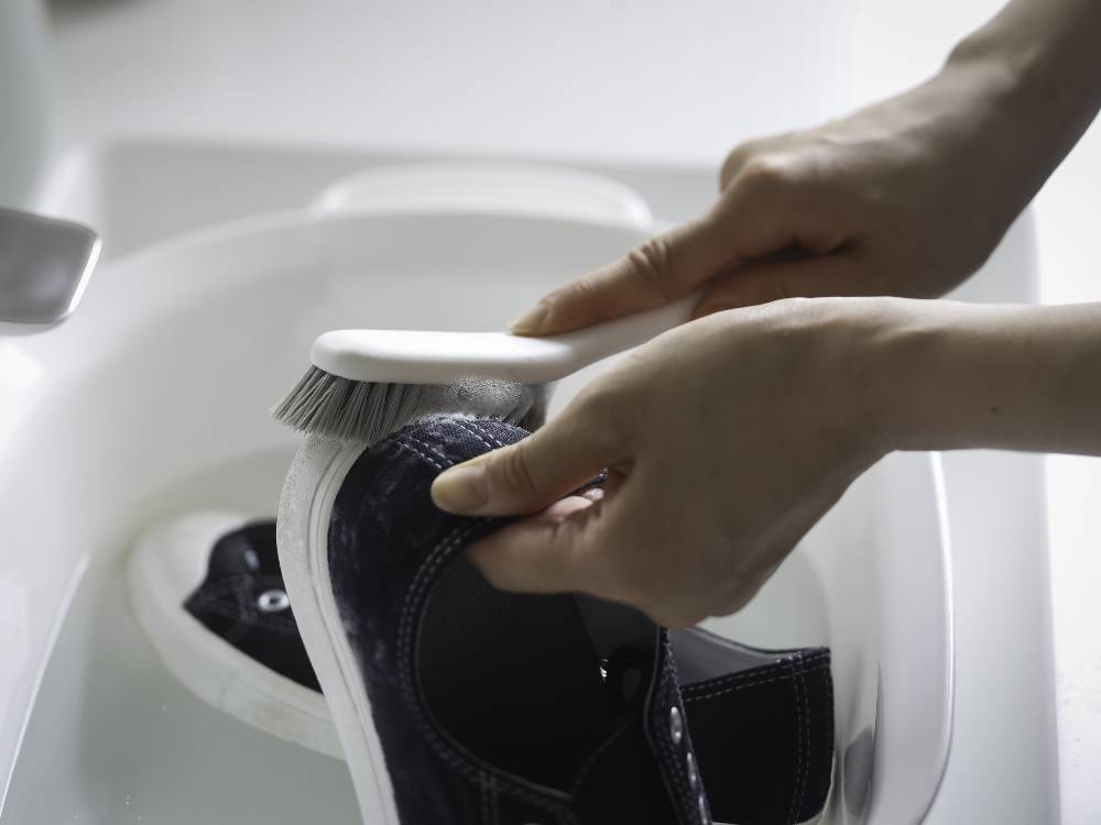 銀色の浴室に設置された【marna/マーナ】きれいに洗えるシューズブラシ。個人ケア用品として使用されています。