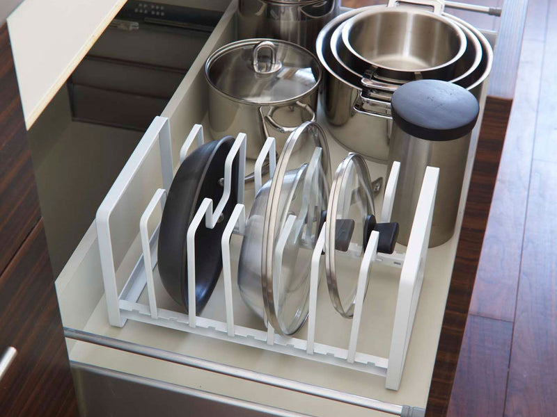 YAMAZAKI製タワー型フライパン＆鍋蓋スタンドがキッチンキャビネット内に設置され、スチールとアルミニウム製の調理器具や食器が整然と並べられています。